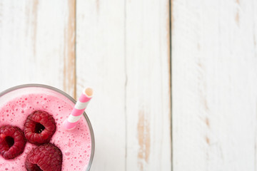 Raspberry smoothie in glass on white wooden table
