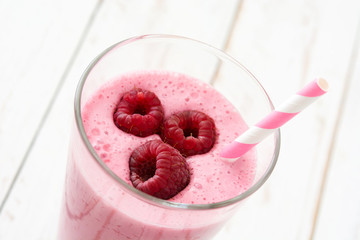 Raspberry smoothie in glass on white wooden table

