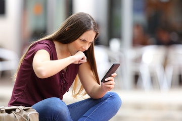 Angry woman with mobile phone in the street