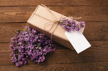 Bouquet of lilacs on a wooden table with a gift box