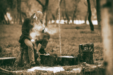 Vape man. Photo of a brutal bearded young man having rest after chop firewood and vaping an...