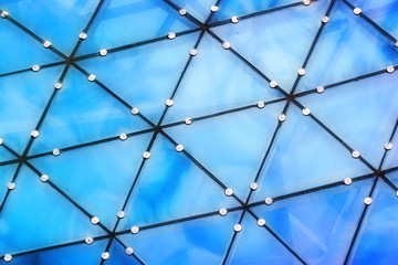 Blue reflections of clouds in glass triangles of transparent roof