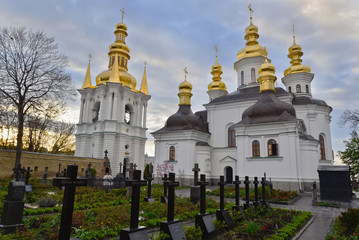 Fototapeta na wymiar Ukraine. Kiev Pechersk Lavra. The church of the Nativity of the Most Holy Mother of God, its belltower and the monastery’s cemetery. Monks’ names and the words “Christ is risen” are on gravestones.
