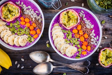 Blueberry smoothies bowl with sea-buckthorn, banana, passion fruit, chia seeds, pumpkin seeds, sunflower and flax seeds