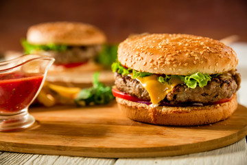 Tasty classic hamburger with beef and tomato sauce on wooden plate. Food concept