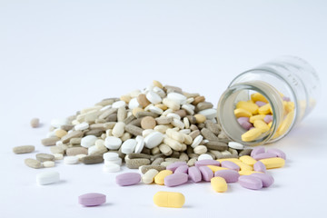 Colorful medical pills in a glass container on a white background.