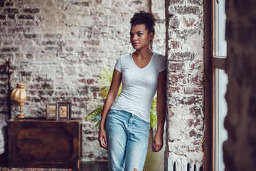 Beautiful african girl in white t-shirt standing at home.