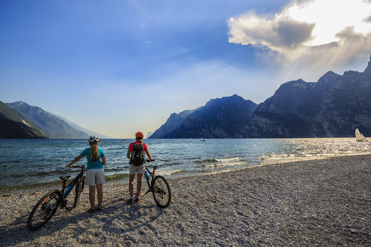 Mountain biking woman and young girl over Lake Garda.