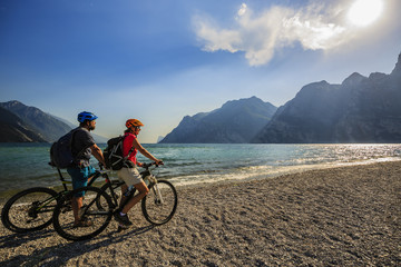 Fototapeta na wymiar Mountain biking, couple with bikes on Lake Garda, Riva del Garda, Italy