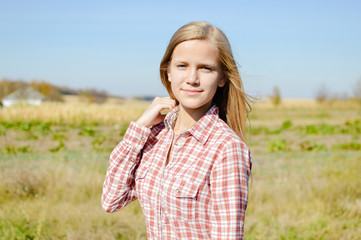Close up portrait of attractive blond young woman standing outdoors on countryside landscape background