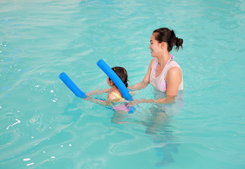 family of mother teaching kid in swimming pool.