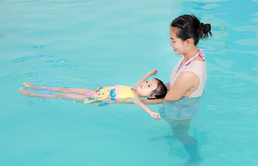 Close up mother teaching kid in swimming pool.