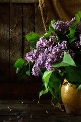 Still life with bouquet of lilac in a clay vase on a wooden background violet flowers with beautiful sun