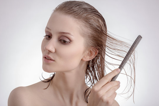 woman combs long wet brown hair on white background
