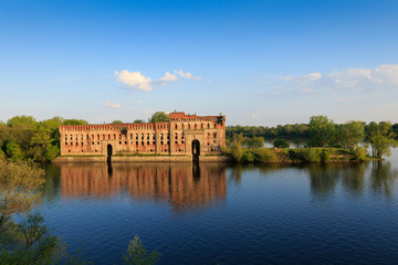 Red brick granary at the river with water reflection
