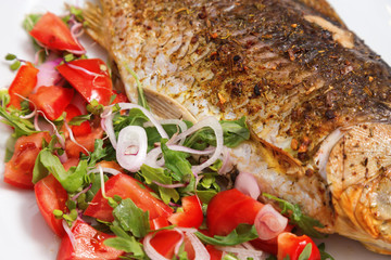 Fish dish. Fried crucian carp with green salad on white plate close-up. Fried freshwater fish with crispy crust from oven. Very taste fish. Healthy food. Hot dish. Second course.