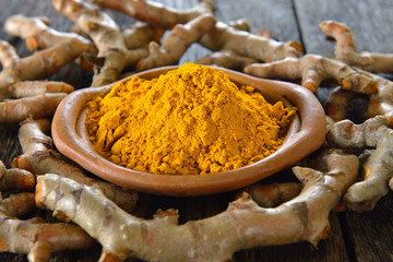 Turmeric powder and turmeric on wooden background