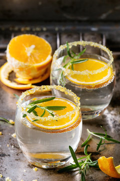 Tonic water cocktail with rosemary and orange. Two glasses with zest sugar and bubbles with textile over dark texture metal background. Refreshing beverage alco non alcohol