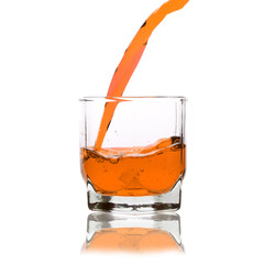 orange cocktail splashing on a glass on white background