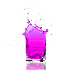 violet cocktail splashing on a glass on white background