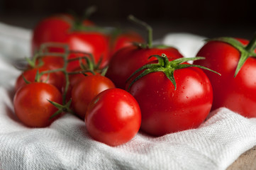 .Ripe tomatoes on a branch of a white napkin, dark background.