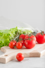 Ripe tomatoes and green salad on the kitchen table, cutting board.Morning light.