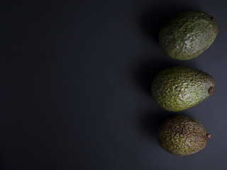 Ripe brown and dark green avocados isolated on black background