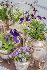 vintage silver tea set used as planters with white and purple flowers