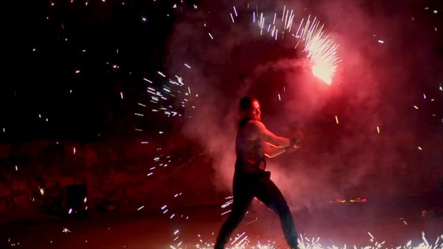 An amazing fire show at night. A man spinning fire. Long shot