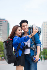Obraz premium Happy tourists taking photo of themselves. summer holidays, travel, vacation, tourism and dating concept - couple taking photo picture with camera