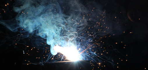Sparks and jets of smoke when welding of steel structures - obrazy, fototapety, plakaty