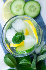 Lemon and cucumber detox water on blue colored wooden background.