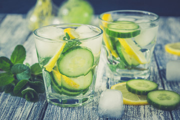 Lemon and cucumber detox water on blue colored wooden background.