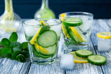 Lemon and cucumber detox water on blue colored wooden background.