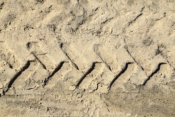 a trail with a tread pattern in the sand from the wheels