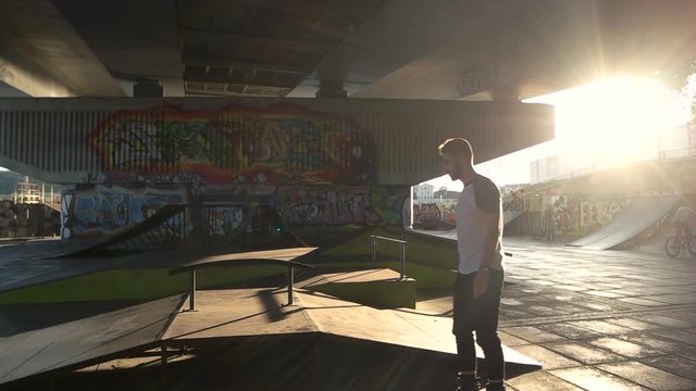 Skatepark with graffiti. Young man on rollerblades outdoor.