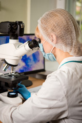 Naklejka na ściany i meble Laboratory assistant or technician in medical research lab looking into a microscope and doing research