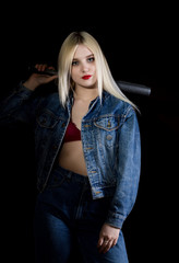 Criminal young woman with baseball bat, young hooligan in jeans and a denim jacket
