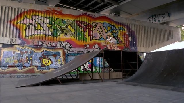Female inline skater in slow-mo. Girl on rollerblades doing trick. Extreme in concrete jungle.