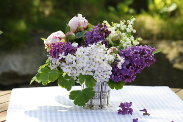 Sommerlicher Blumenstrauss auf Gartentisch mit Pfingstrosen,Maiglöckchen und Flieder