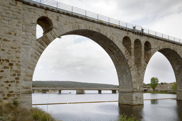 Fototapeta premium Old stone bridge for railroad crossing a dam next to a highway 