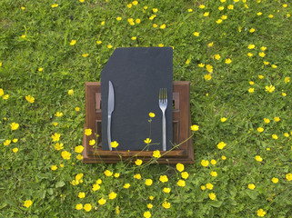 ardoise carte de menus posée sur un lutrin dans une prairie fleurie pour restaurant, bar, auberge.