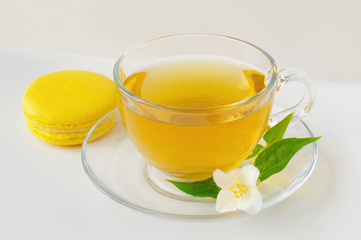 Tea cup with green tea, fragrant Jasmine flowers, tea leaves and Macaroon in the white background