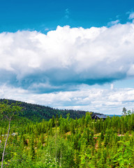 Landscape with old wooden houses and mountains covered by clouds