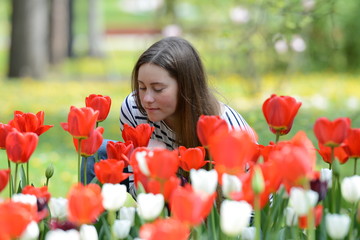 Naklejka premium Portrait of beautiful young woman with many tulips in the park.