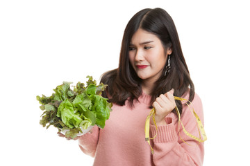 Unhappy Asian woman with measuring tape and salad.