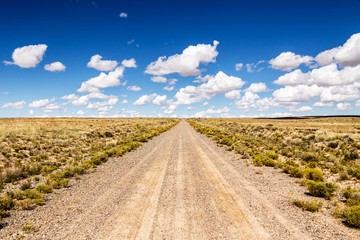 lonelyness on infinite dirt road in the desert with clouds