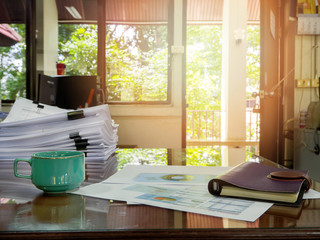 Close up of a cup of coffee and office supplies on desk in office at morning, warm tone