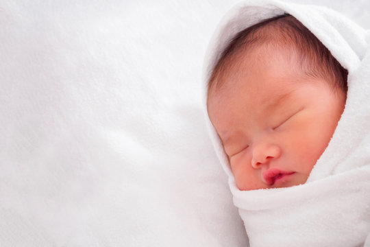 Cute newborn asian baby girl sleeping on white fabric