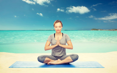 Fototapeta na wymiar woman meditating in lotus yoga pose on beach 